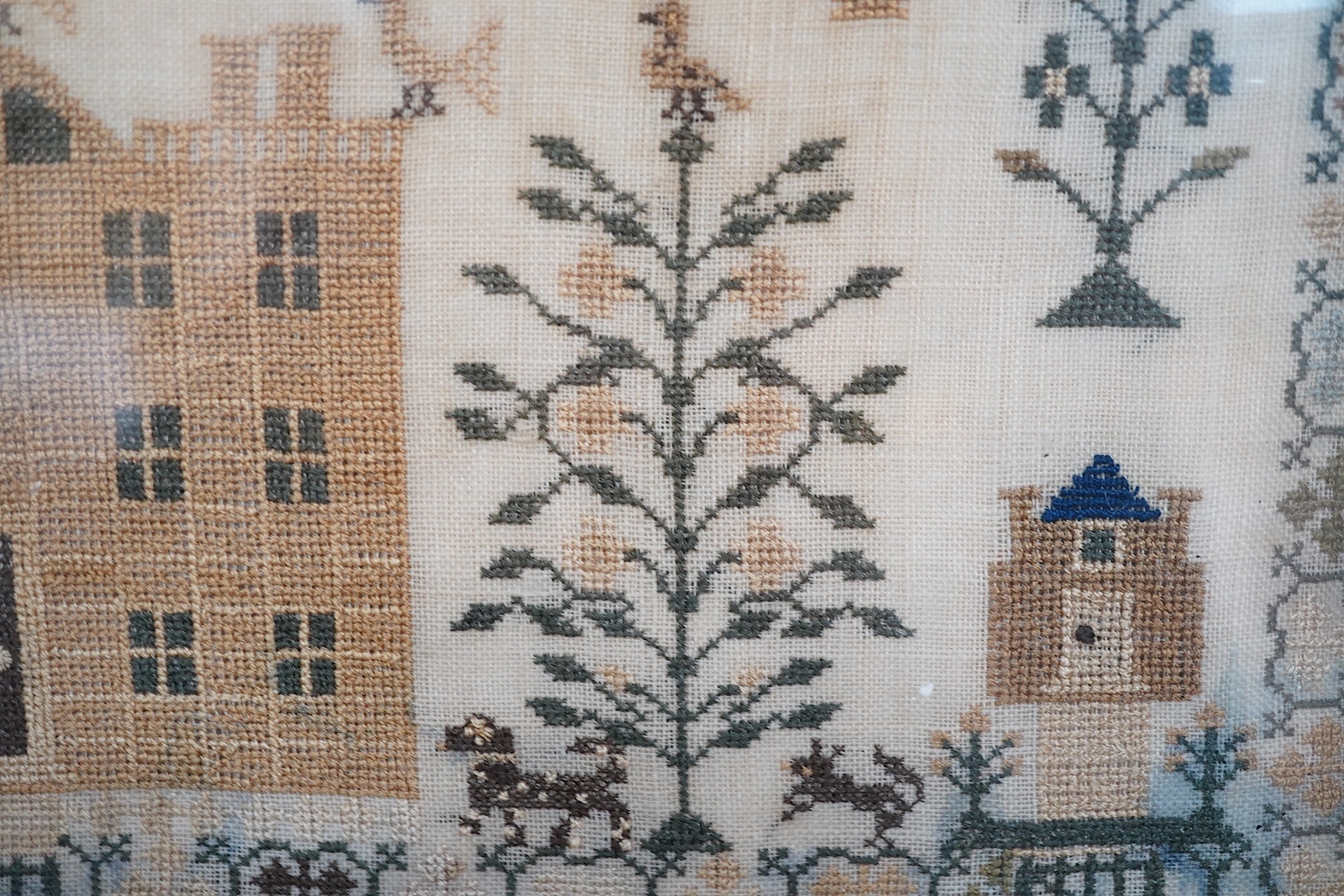 A framed 1835, dated sampler, embroidered by Mary Walker, worked in fine coloured silks, with a central verse and large three storey house, trees, dogs, deer and rabbits, below a panel of embroidered trees, flowers and b